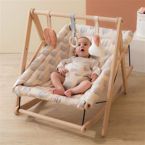 Illustration einer stilisierten Babywippe mit einem Baby darin, umgeben von Haushaltsgegenständen wie einem Kochtopf und einem Buch.