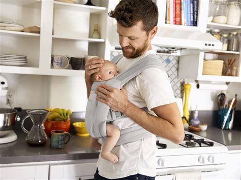 Foto einer Familie, die eine Babytrage nutzt, mit Fokus auf die entspannte Haltung von Eltern und Kind