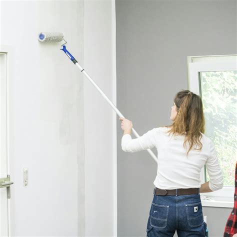 Eine Kommode wird sorgfältig mit einer Malerrolle lackiert