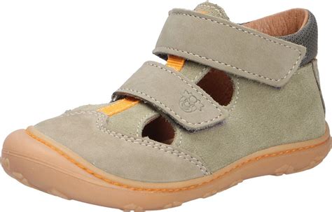 Kinderschuhe von Ricosta in gelber Farbe, die auf den Füßen eines Kleinkindes getragen werden.