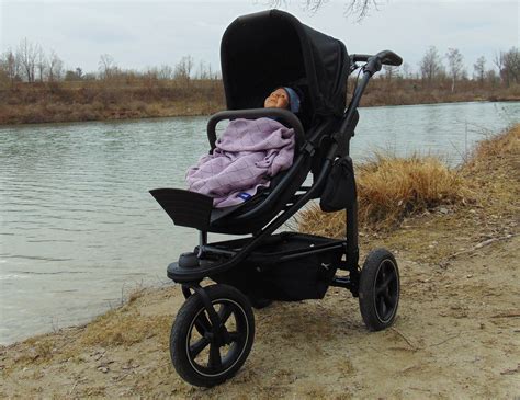 Eine Familie mit einem Kind im TFK Kinderwagen, das in den Fußsack eingepackt ist, bei einem Spaziergang im Winter
