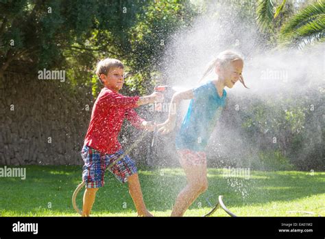 Kinder spielen fröhlich mit Wasser im Garten an einem sonnigen Tag.