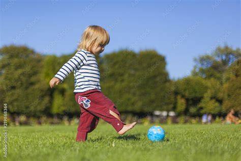 Kind mit Lauflernschuhen, das auf einer Wiese spielt