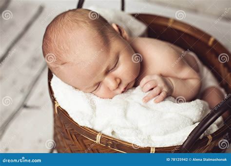 Neugeborenes Baby schlafend in einem Korb, umgeben von weichen Decken.