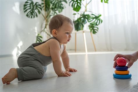 Ein Baby im Alter von etwa 12 Wochen, das begeistert nach einem bunten Spielzeug greift.