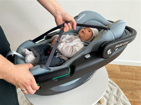 Illustration einer Babyschale, die sicher im Auto befestigt ist, mit Fokus auf die Gurtführung.