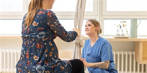 Frau mit Baby im Arm, die von einer Hebamme unterstützt wird