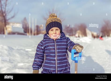 Kind im Winter in einem warmen Overall mit Mütze und Handschuhen