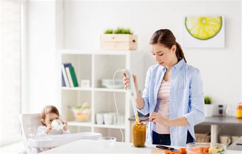 Eine Mutter, die in der Küche kocht, während ihr Baby sicher in einer Babywippe daneben sitzt.