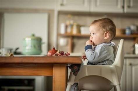 Baby sitzt sicher und aufrecht in einem Hochstuhl am Familientisch.