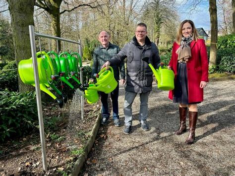 Foto von Geschäftsinhaberinnen, die Gießkannen erhalten, vor bepflanzten Kübeln in Dieburg