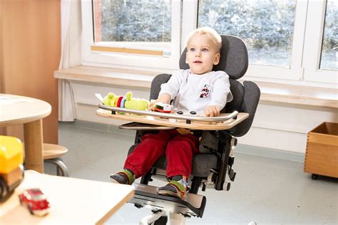 Ein Kind sitzt bequem und sicher in einem Therapiestuhl mit angepassten Armlehnen und Fußstütze.