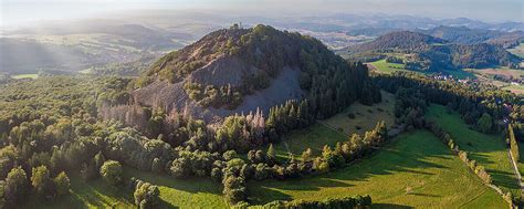 Panoramablick auf die sanften Hügel der Rhön mit vereinzelten Bäumen und blühenden Wiesen