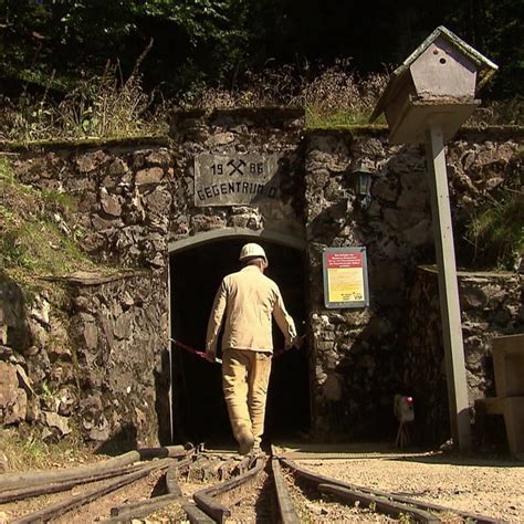 Kinder blicken neugierig in einen beleuchteten Schaustollen eines Bergwerks