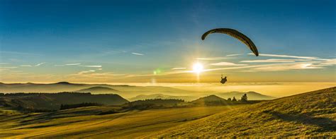 Gleitschirmflieger schweben über der Wasserkuppe, im Hintergrund die Radarstation