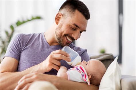Vater füttert Baby mit abgepumpter Muttermilch aus einer Flasche