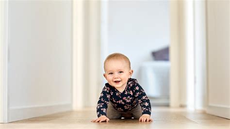 Baby, das auf allen Vieren krabbelt, umgeben von bunten Spielzeugen