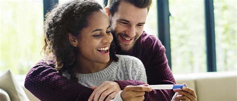 Paar, das sich freut, einen positiven Schwangerschaftstest in der Hand zu halten