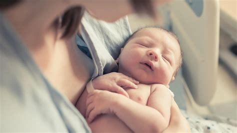 Mutter hält ihr Neugeborenes im Arm, Zeichen von Bonding