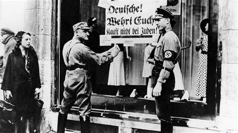 Historische Fotos von jüdischen Männern, die zur Arbeit gezwungen werden, mit Spott-Transparenten während der NS-Zeit.
