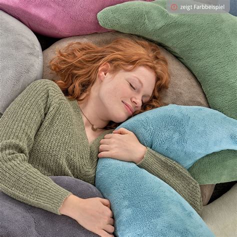 Eine Frau entspannt sich mit dem Theraline Plüschmond Stillkissen auf dem Sofa.