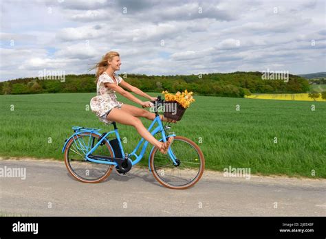 Eine schwangere Frau fährt entspannt auf einem Fahrrad durch eine grüne Landschaft.
