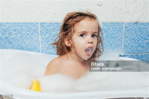 Ein kleines Kind planscht fröhlich in einer Badewanne mit Schaum.