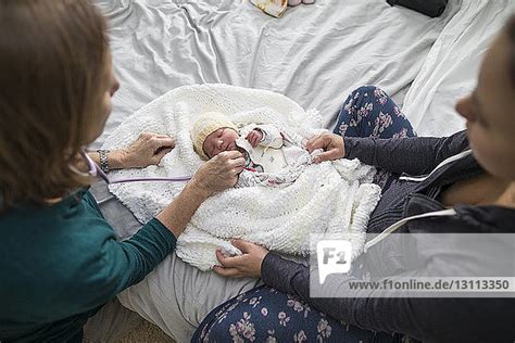 Hebamme untersucht ein Neugeborenes zu Hause bei der Familie.