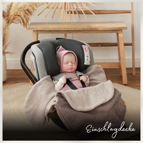 Schema, das die Funktionsweise einer Einschlagdecke mit Gurtschlitzen in einer Babyschale zeigt.