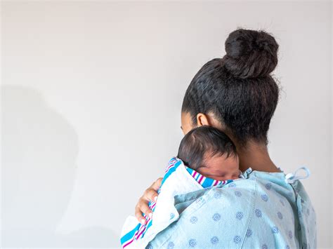 Hebamme unterstützt eine frischgebackene Mutter mit ihrem Baby