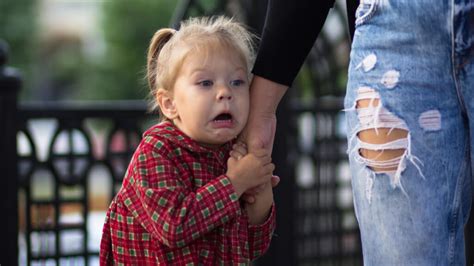 Ein Baby, das sich ängstlich hinter der Mutter versteckt, während eine fremde Person näher kommt.