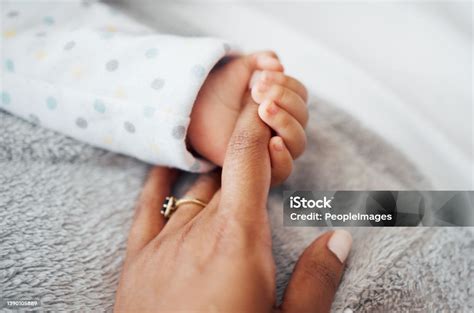 Foto einer Mutter, die sanft die Hand ihres Babys hält, das versucht, an ihren Haaren zu ziehen.