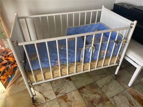 Schemazeichnung, die zeigt, wie eine Gitterseite von einem Kinderbett entfernt wird.