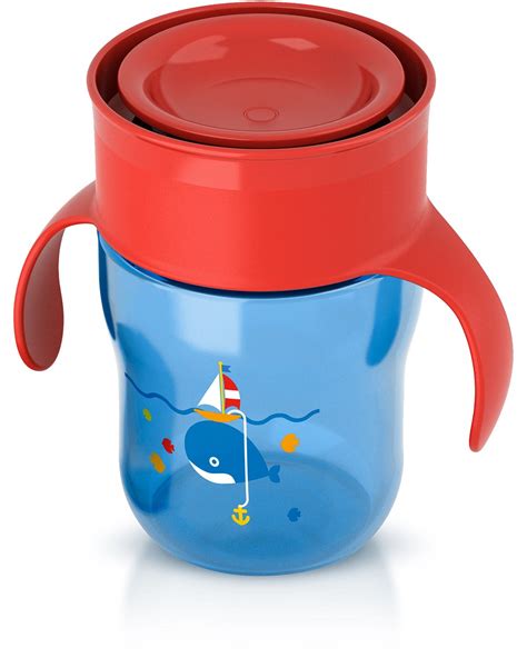 Foto eines Kindes, das fröhlich aus einem Philips Avent Trinklernbecher trinkt, auf einem Tisch neben einem Bett.