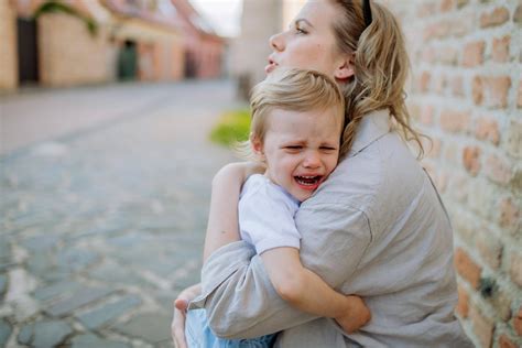 Eine Mutter hält ihr weinendes Kind tröstend in den Armen.