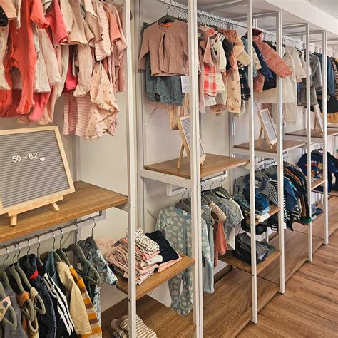 Innenansicht eines gut organisierten Second-Hand-Ladens für Kinderkleidung mit Regalen voller Kleidung und Spielzeug.