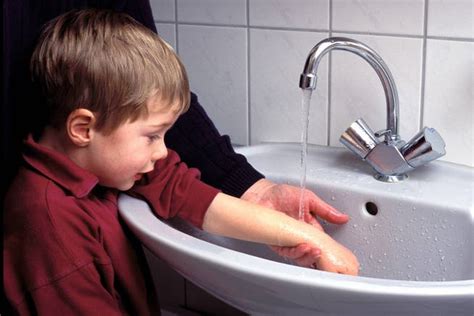 Kind mit leichter Verbrennung an der Hand, das unter fliessendem Wasser gekühlt wird