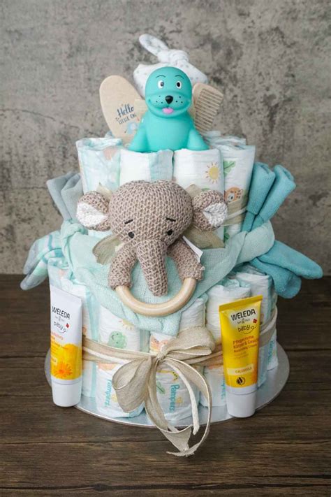Kind hält eine bunte Windeltorte mit Baby-Accessoires