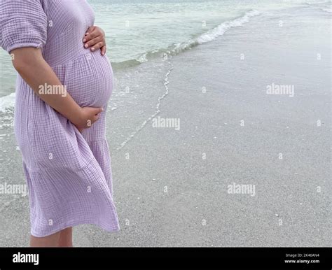 Symbolbild einer schwangeren Frau, die entspannt am Strand sitzt, mit einer stilisierten Weltkarte im Hintergrund.