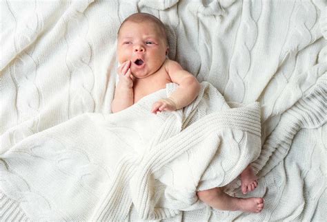 Neugeborenes Baby nackt auf einer schlichten, grauen Decke liegend