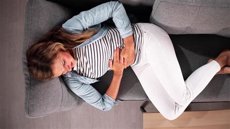 Eine Frau liegt entspannt auf dem Bauch, unterstützt durch ein Schwangerschaftskissen.