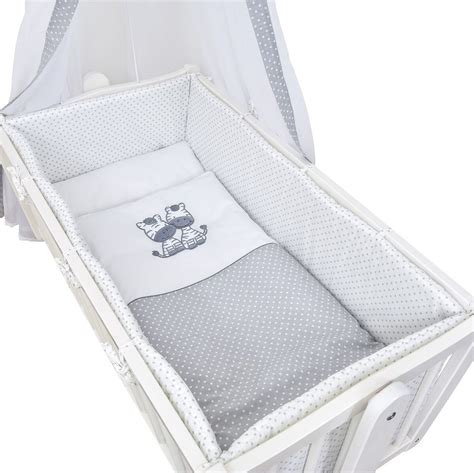 Ein 6-teiliges Wiegenset in Beige mit Chiffonhimmel, Nestchen und Bettwäsche.