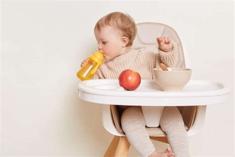 Ein Baby sitzt in einem Hochstuhl und isst begeistert mit den Händen.