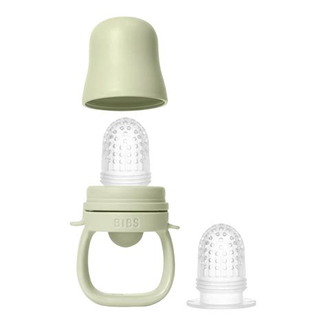 Baby mit Fruchtsauger, der Gurkenstücke enthält