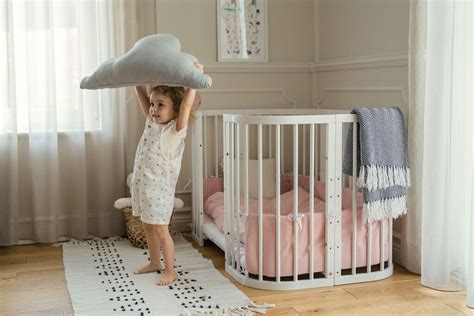 Kind legt Arme über dem Kopf in einem Babybett aus Holz