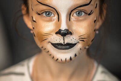Kind mit bunt geschminktem Gesicht als kleiner Tiger