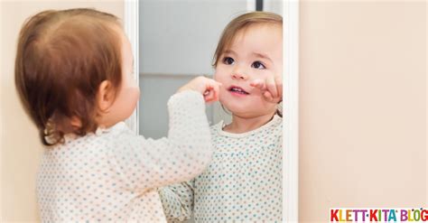 Kind, das sich im Spiegel betrachtet und lacht, mit geschminktem Gesicht