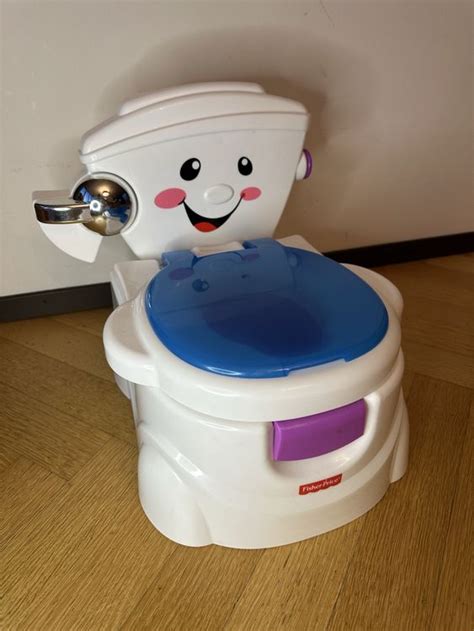 Detailansicht des Fisher-Price Töpfchens mit hervorgehobenem Ein-/Ausschalter und Toilettenpapierhalter