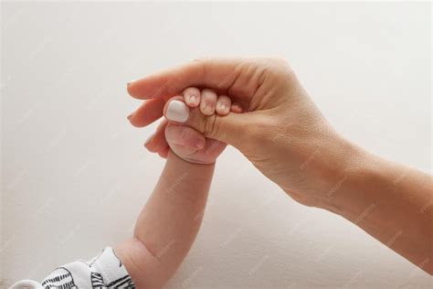 Eine Hand, die sanft die Hand eines Neugeborenen hält, symbolisiert den zarten Moment des Abschieds und die Bedeutung von Berührung.